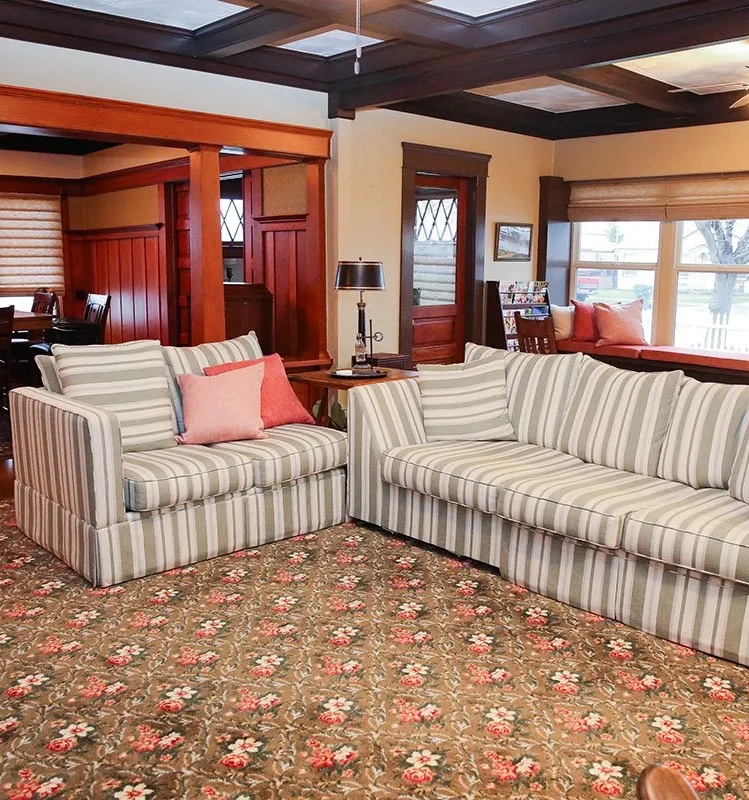 Living area with two striped sofas and floral carpet