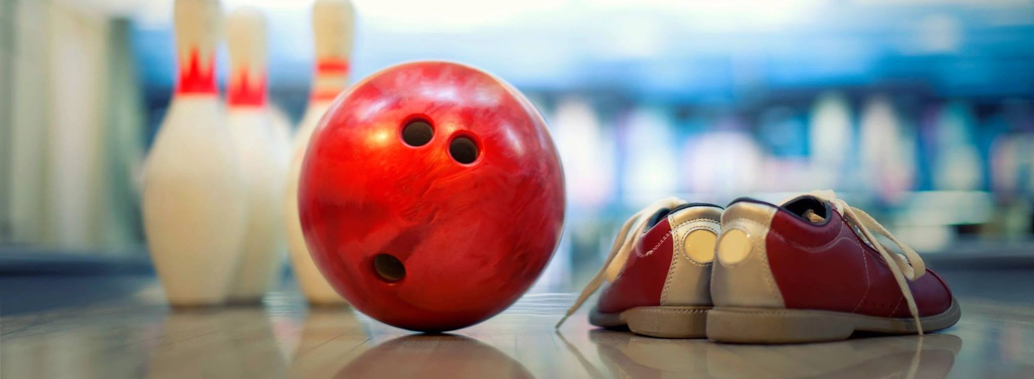Red bowling ball, with shoes in foreground, pins in background