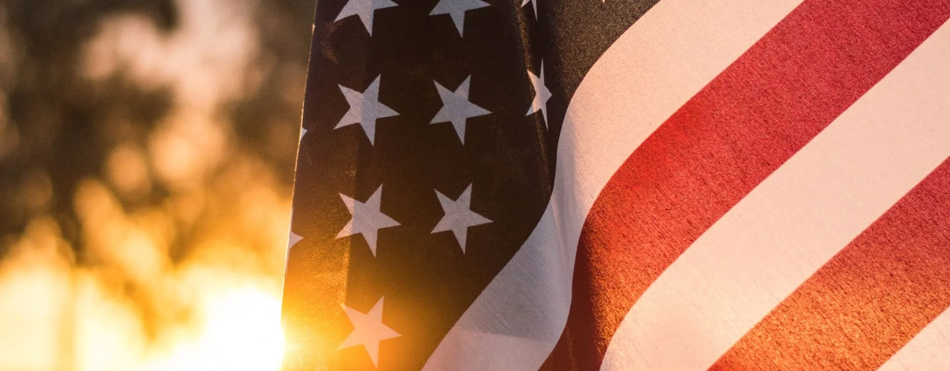 Close up of portion of U.S. flag with burning candles in background