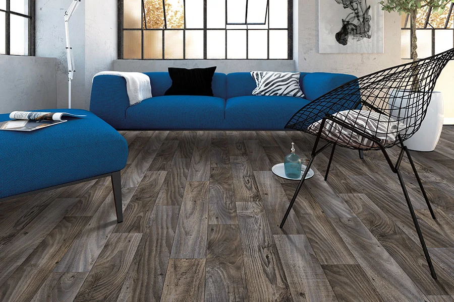Laminate flooring that looks like dark wood in contemporary sitting room with blue cushioned couch and wire chair