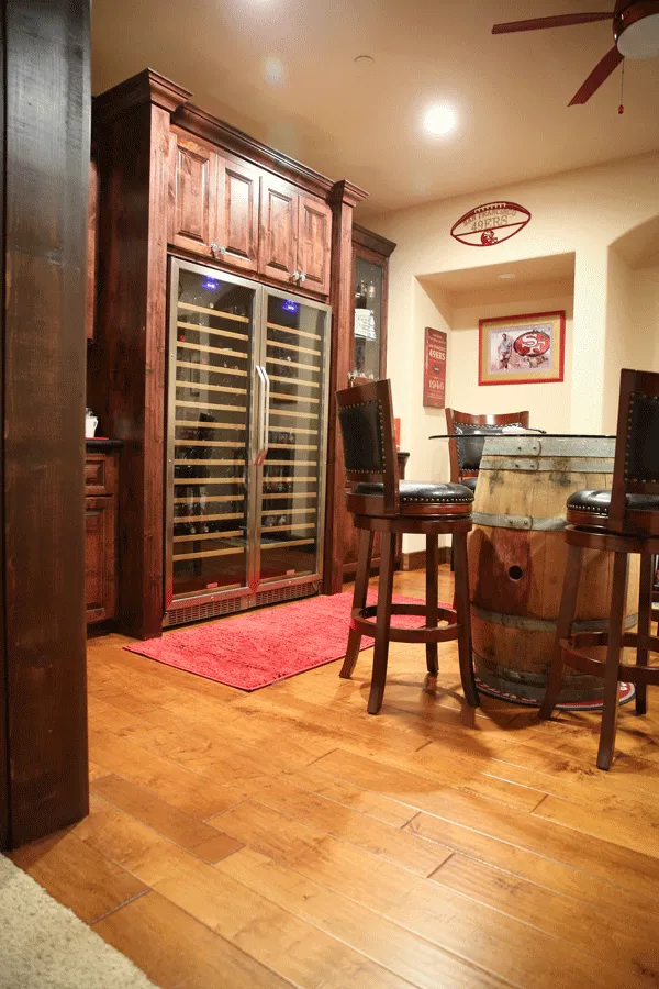 Area with wine fridge, barrel cocktail table on hardwood plank flooring in Shaver Lake, CA