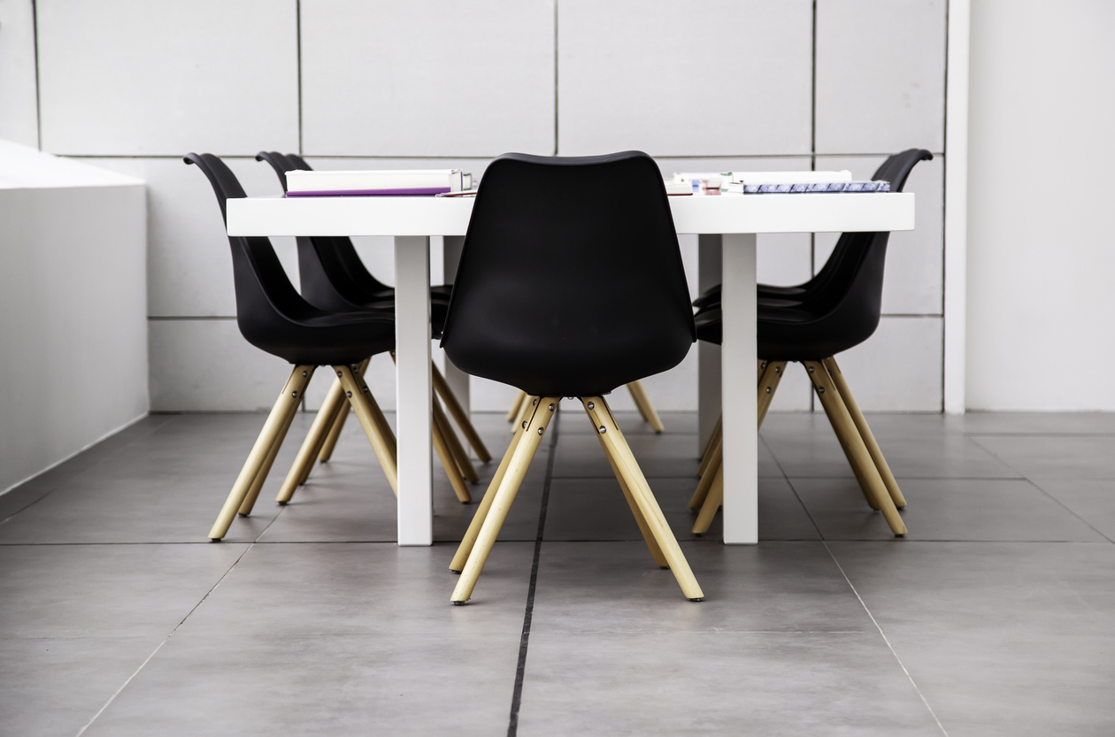 Small table and chairs on very large gray LVT flooring squares